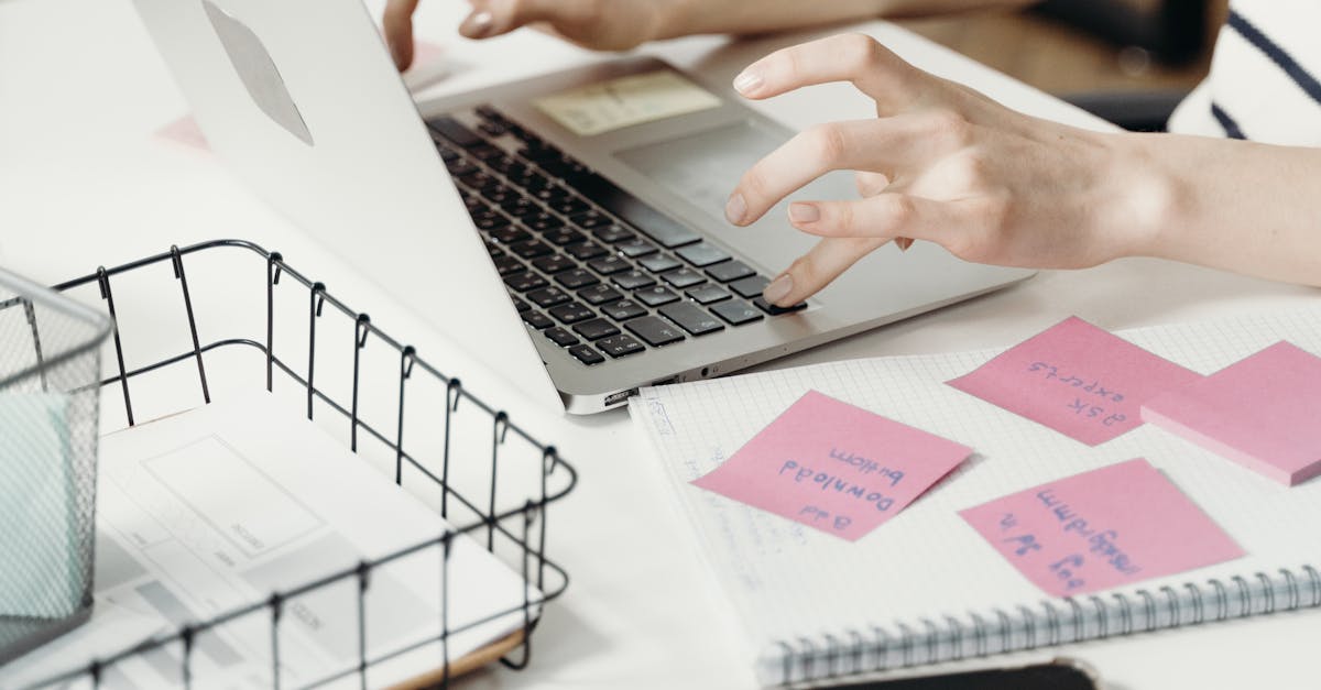 A-woman-working-on-a-laptop-surrounded-by-sticky-notes-paper-and-a-phone-in-a-modern-office-setting