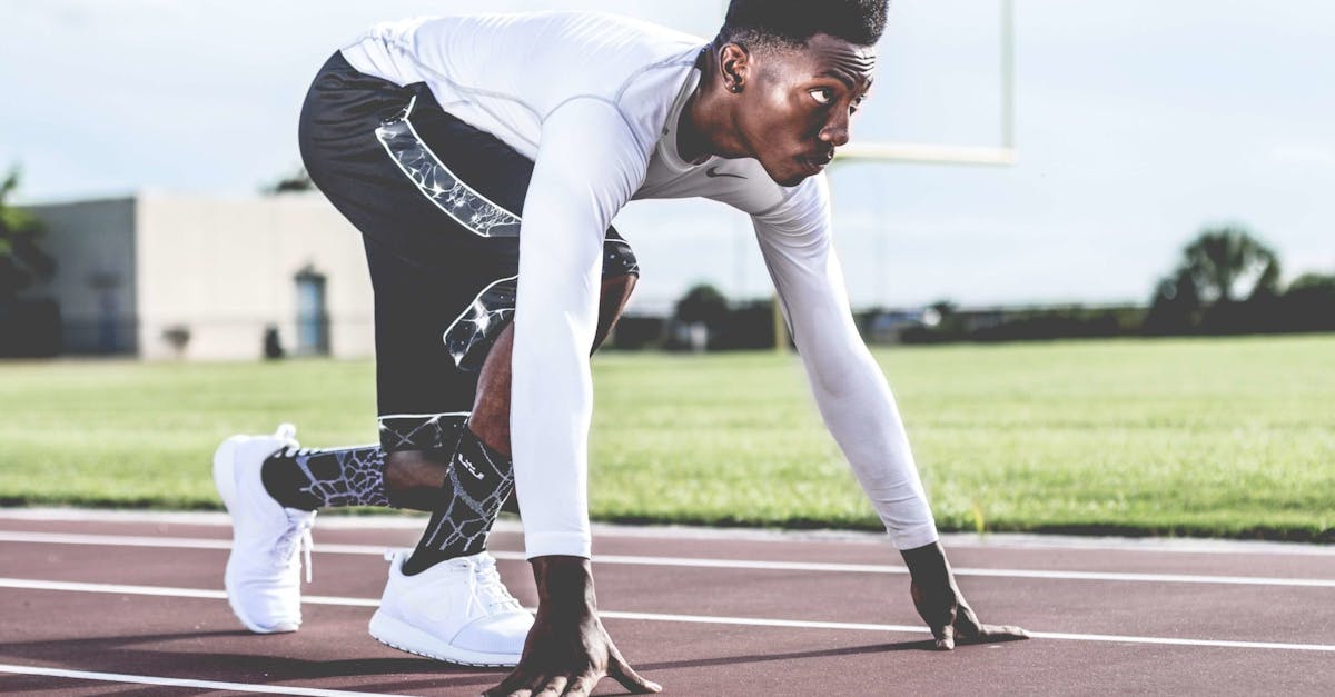 Focused-athlete-in-starting-position-on-a-sunny-track-field-ready-to-sprint